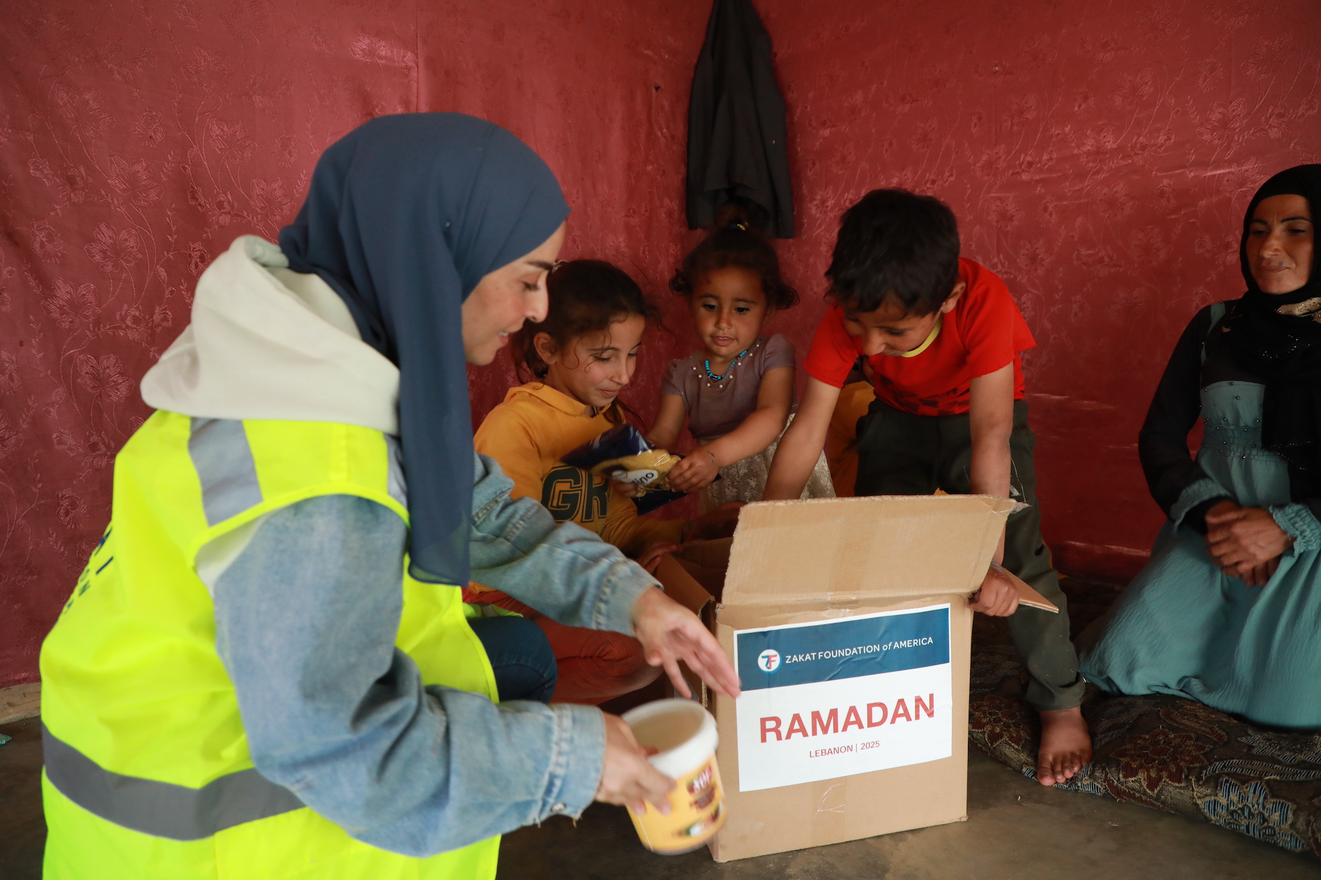 A family excitedly opens their Ramadan food package to see the foods inside