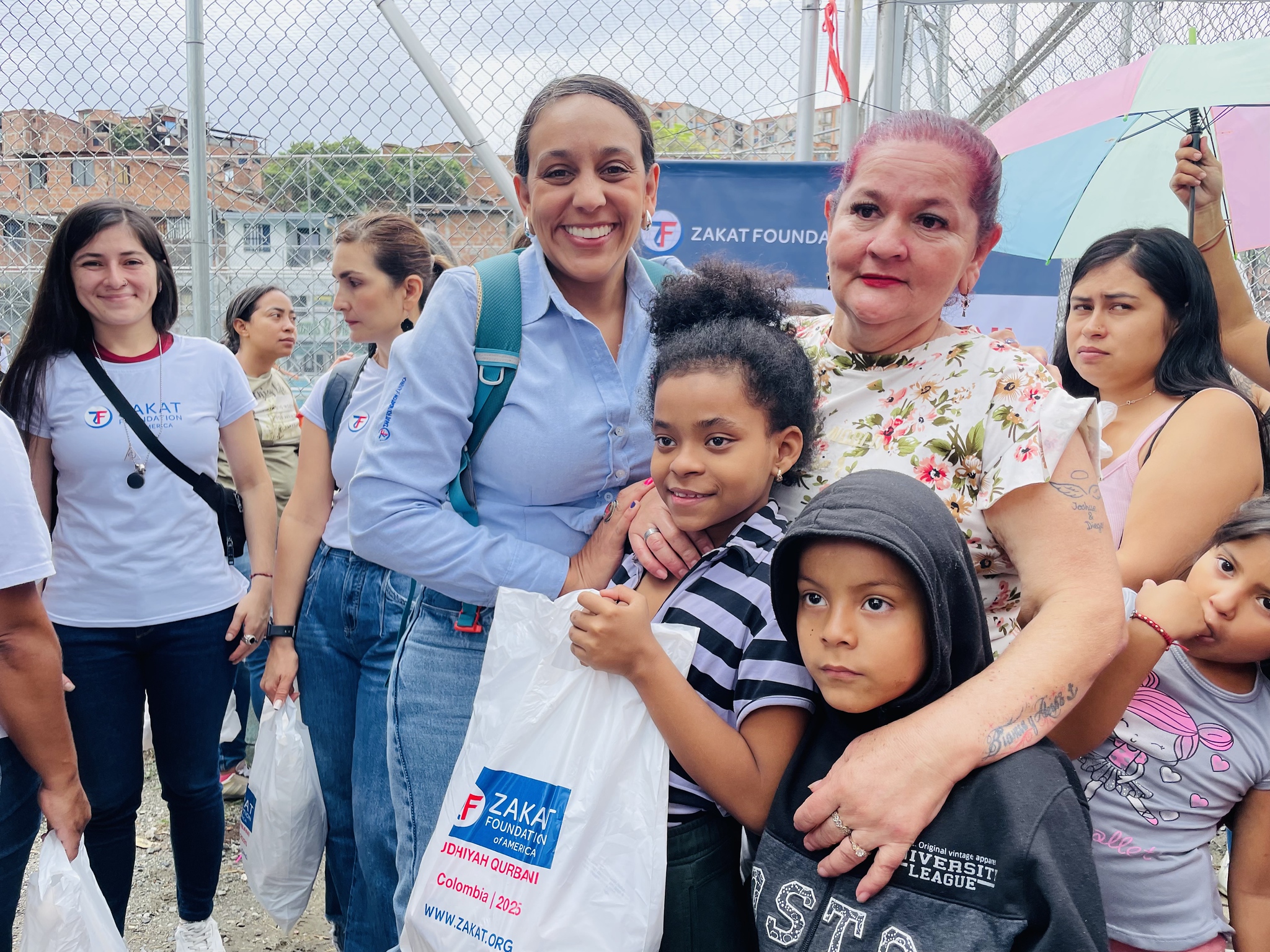 A mother in Colombia holds her children tight after collecting her Udhiyah meat