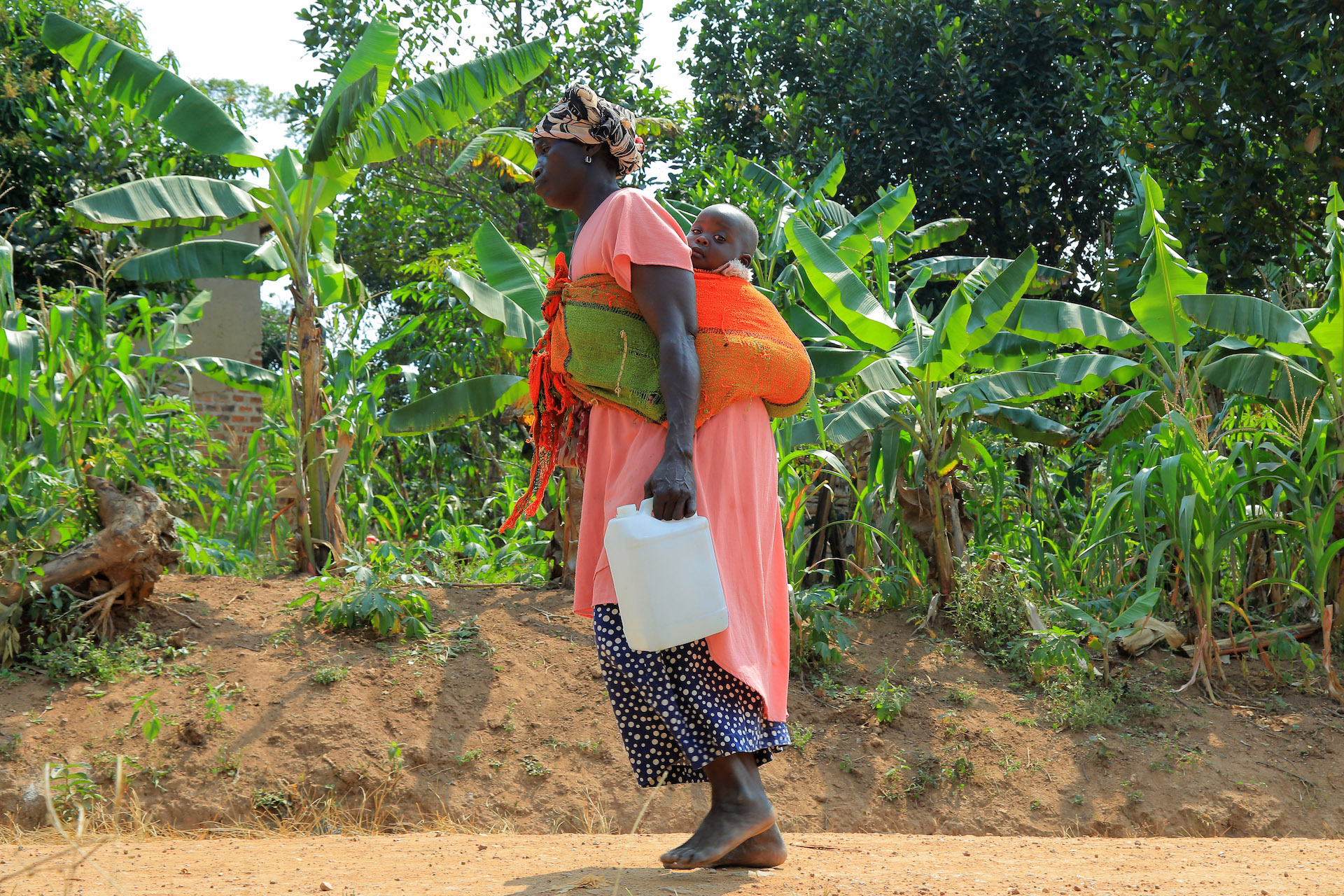 A mother in Uganda collects water at our newly installed water pump