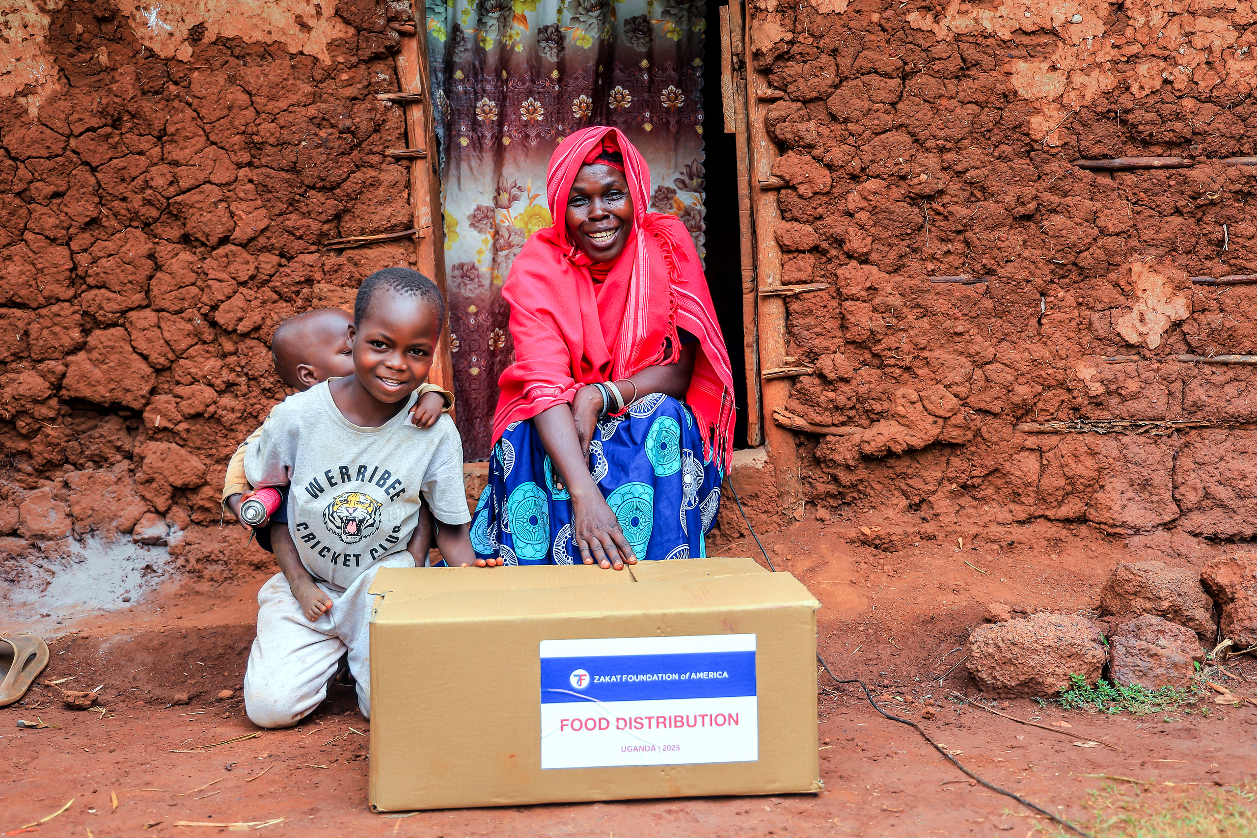 A mother in Uganda smiles with her children after receiving our Ramadan food package