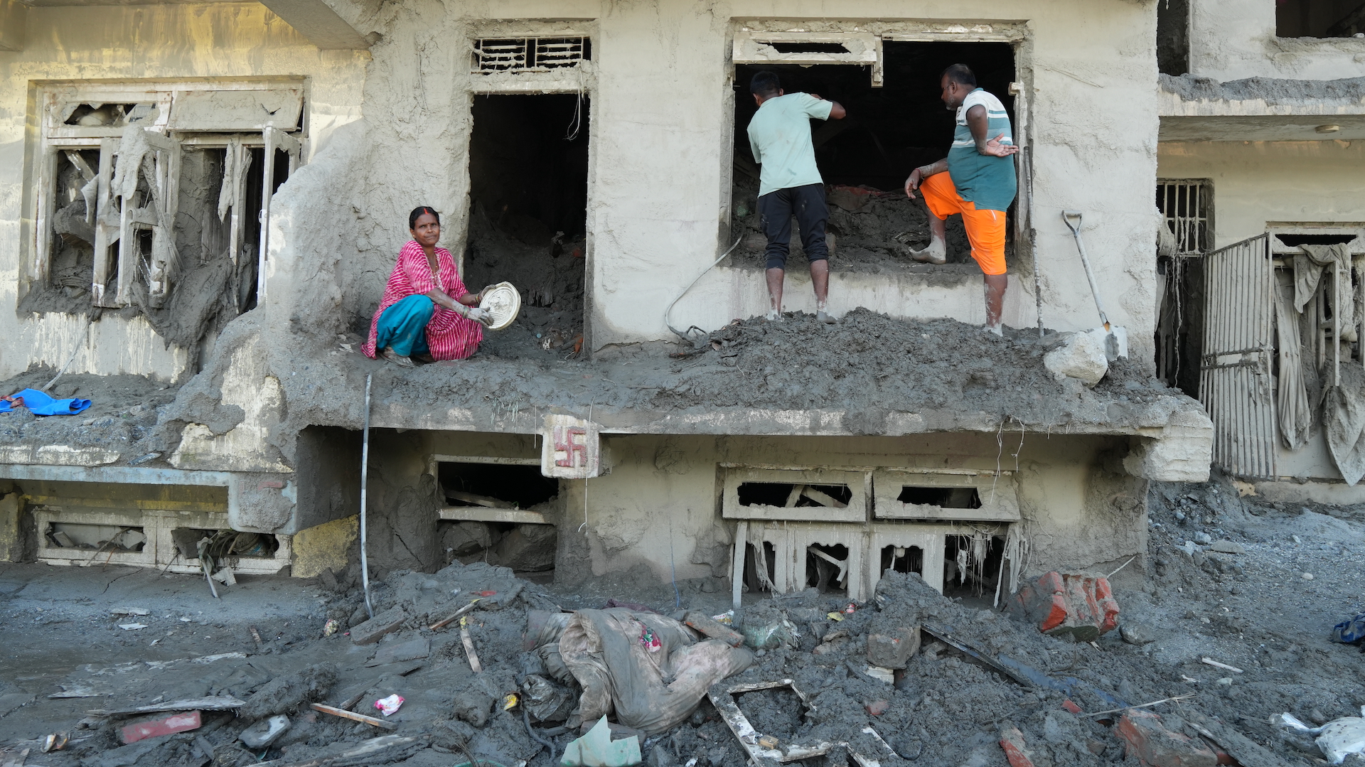 A Nepali family attempts to salvage their belongings in the aftermath of receding flood waters