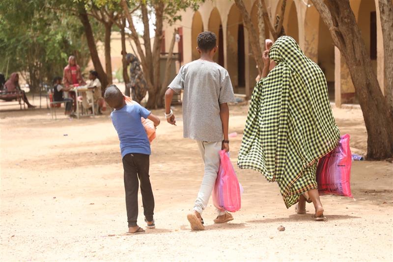 A Sudanese mother walks home with her children after receiving a food package that will give them nourishment