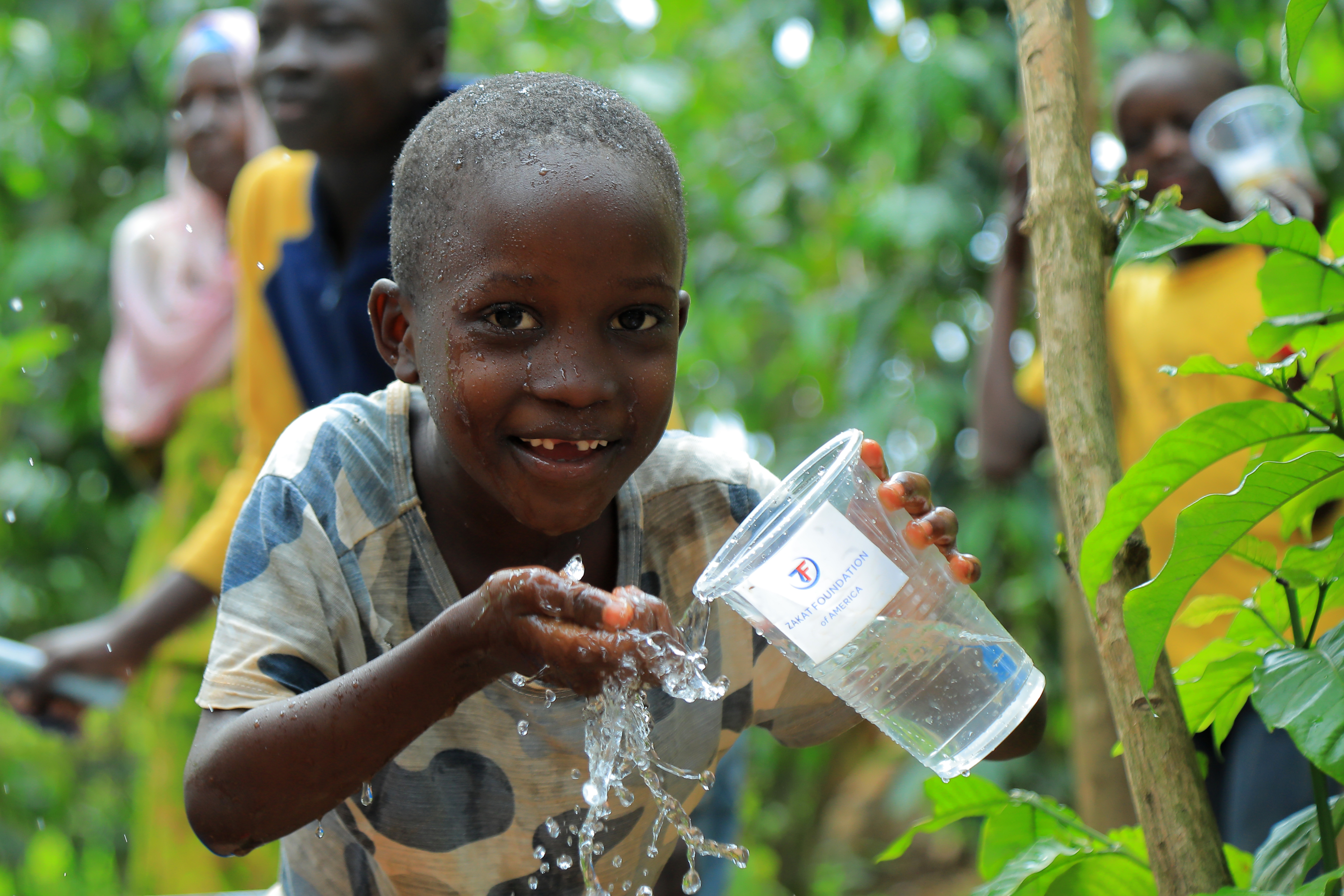 A young boy in Uganda cools off at our newly installed water pump