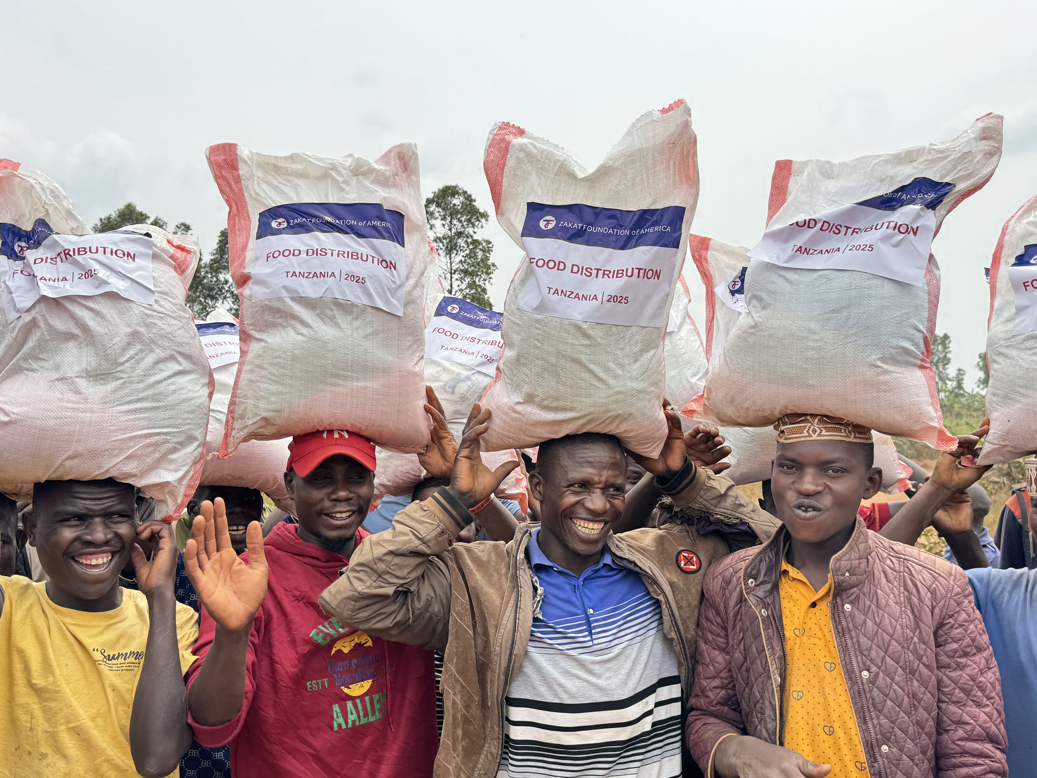 Men in Tanzania carry Ramadan food packages back home with smiles and relief
