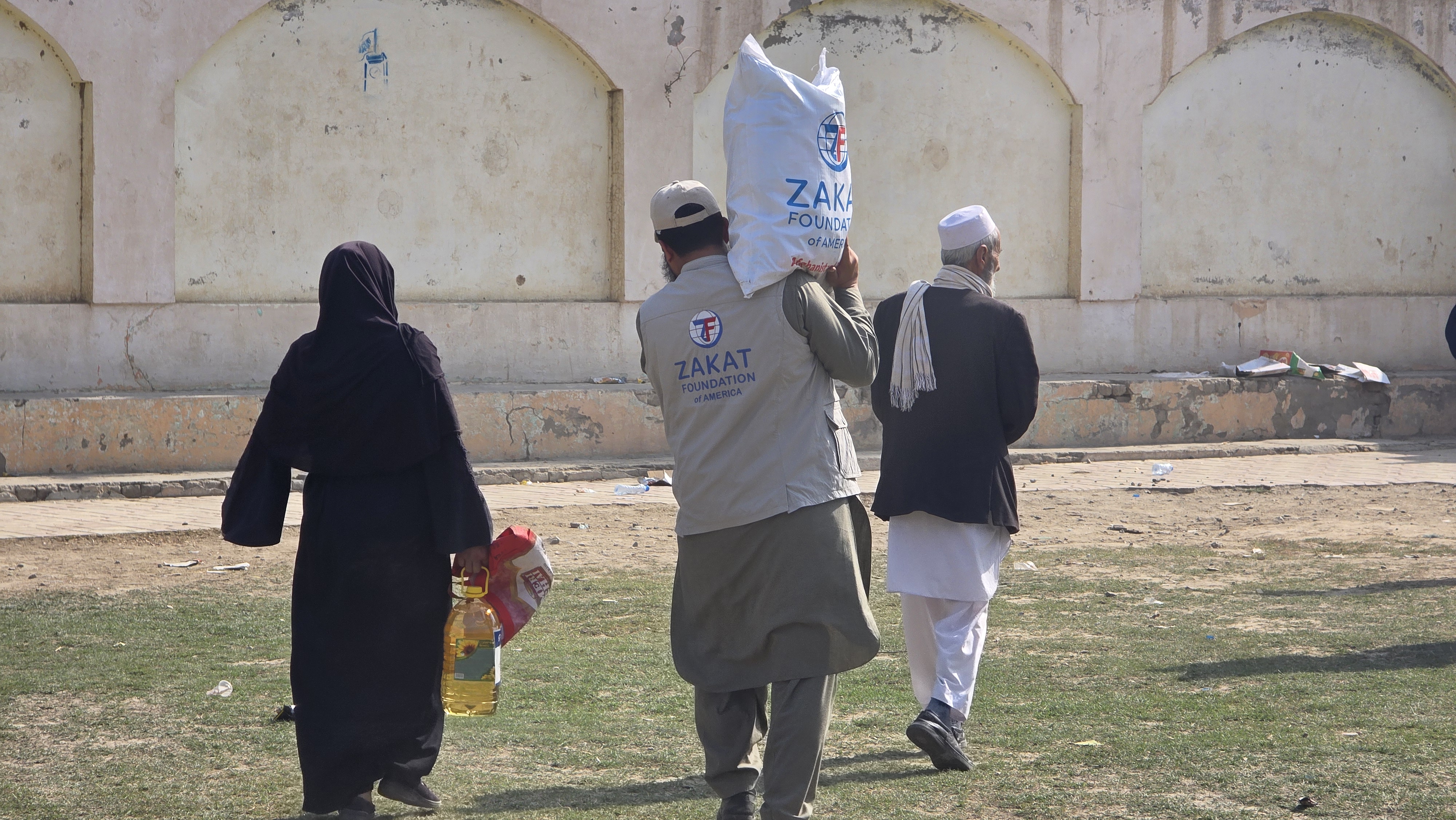 Our team member helps an elderly Afghan refugee family carry home food parcels