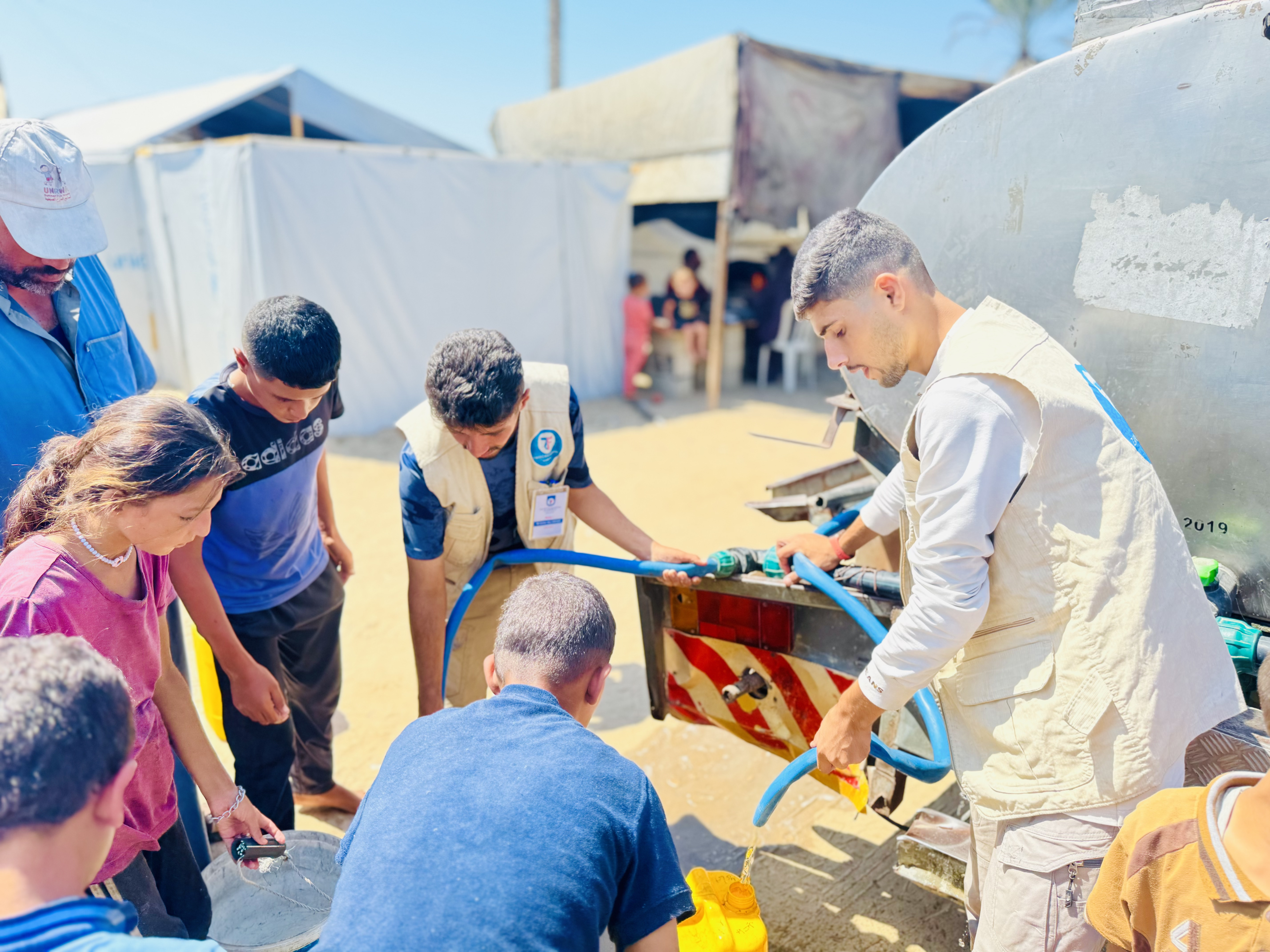 Our team members assist families in Gaza as they fill their water jugs