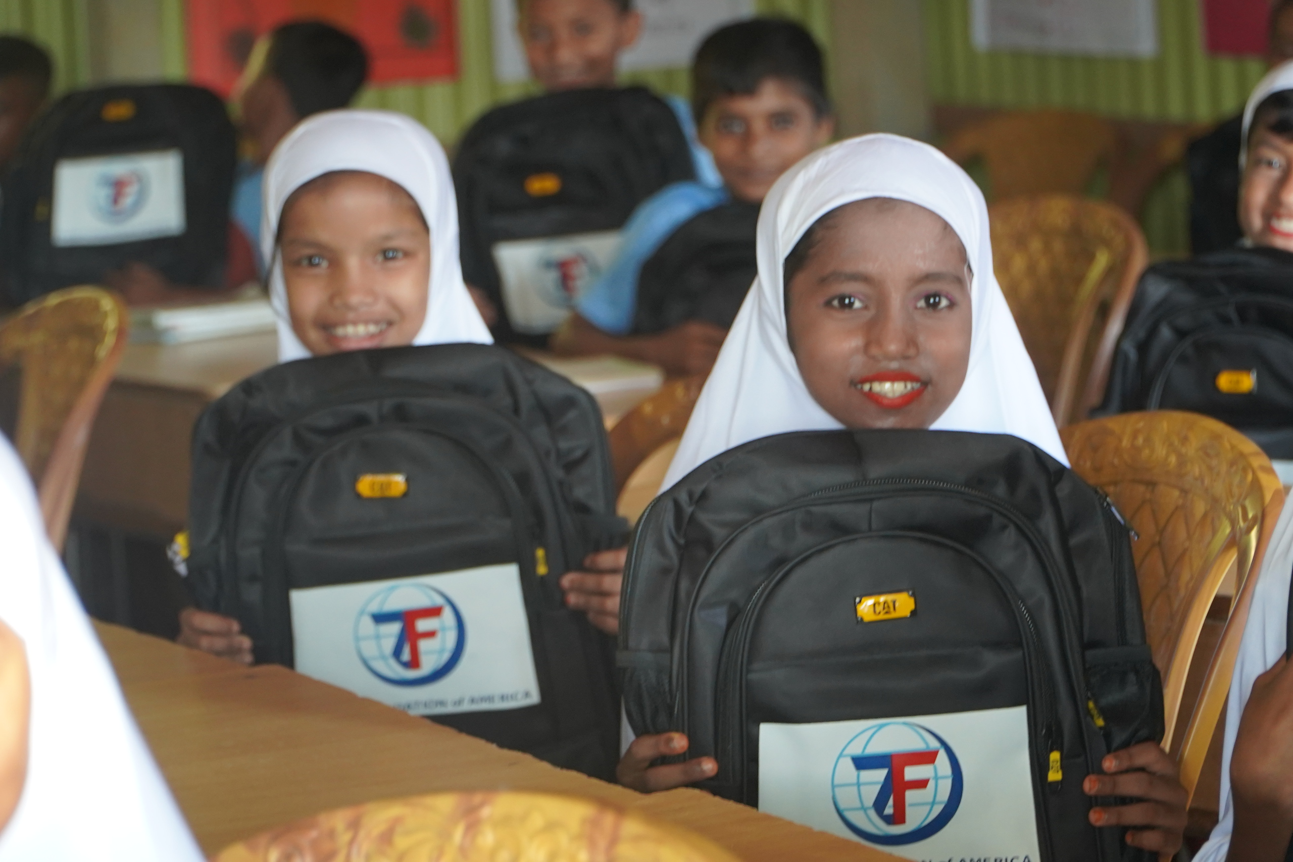 Two young girls at our Rohingya Learning Center in Bangladesh are show their excitement at new school supplies