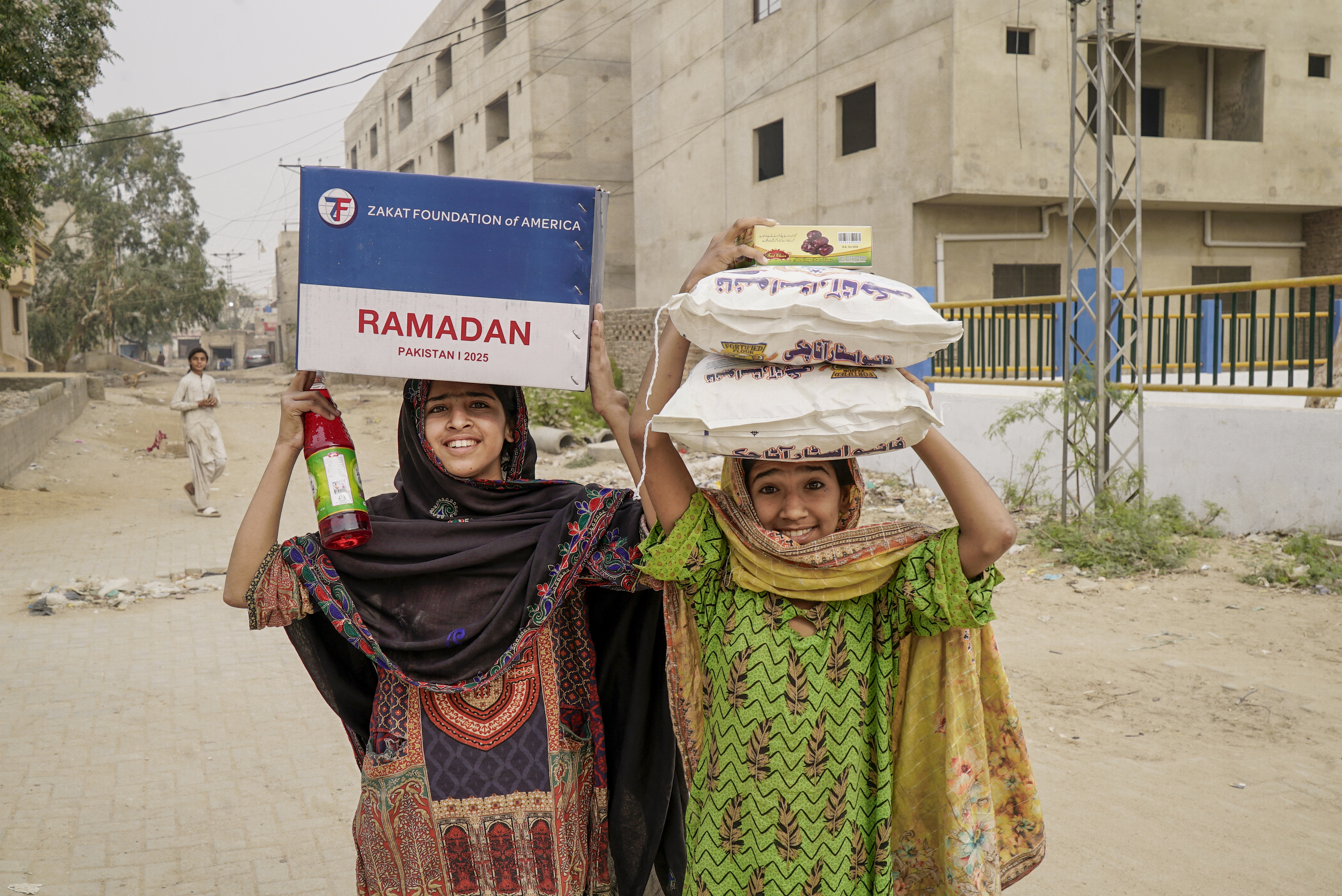 Young girls in Pakistan are excited to bring home their Ramadan food package